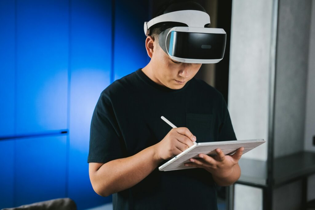 A man indoors wearing a VR headset while writing on a tablet with a stylus pen. Trusted AI tools for creators and freelancers recommended with confidence.