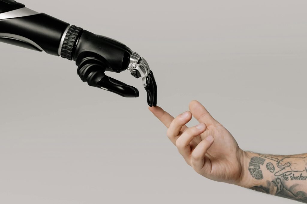 A human hand with tattoos reaching out to a robotic hand on a white background. Human hand touching robot hand symbolizing connection and AI tools for creators.